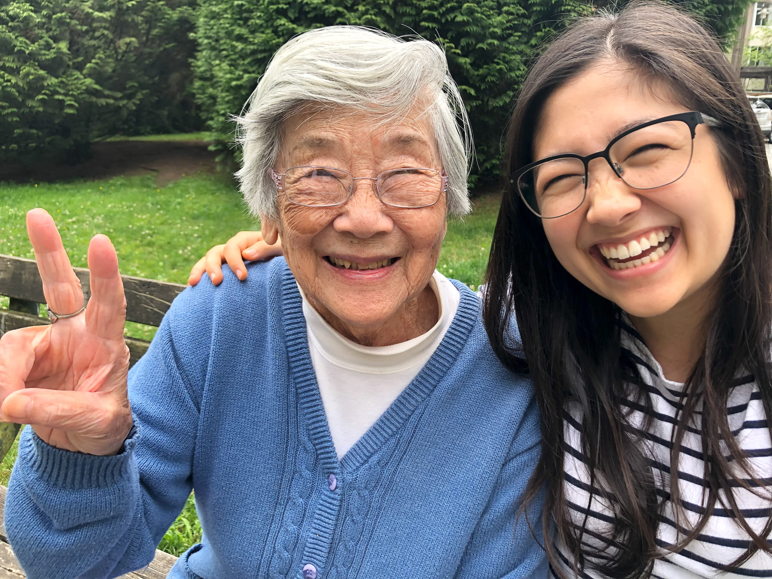 Asian Grandmother and Eurasian Granddaughter Smiling for Photo on Bench